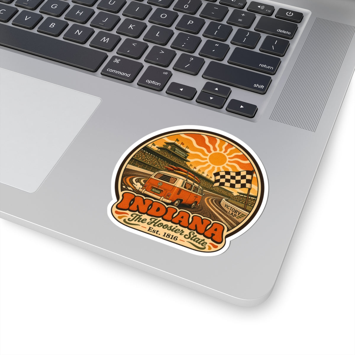 Round racing van sticker on laptop keyboard with orange sunburst and checkered flag