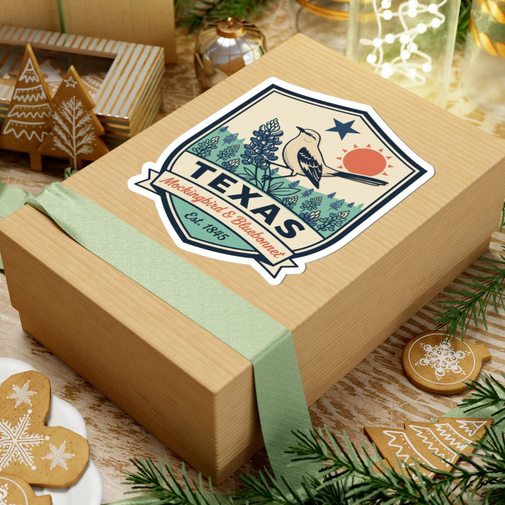Texas badge sticker on gift box, mockingbird and bluebonnet scene with TEXAS and Est. 1845