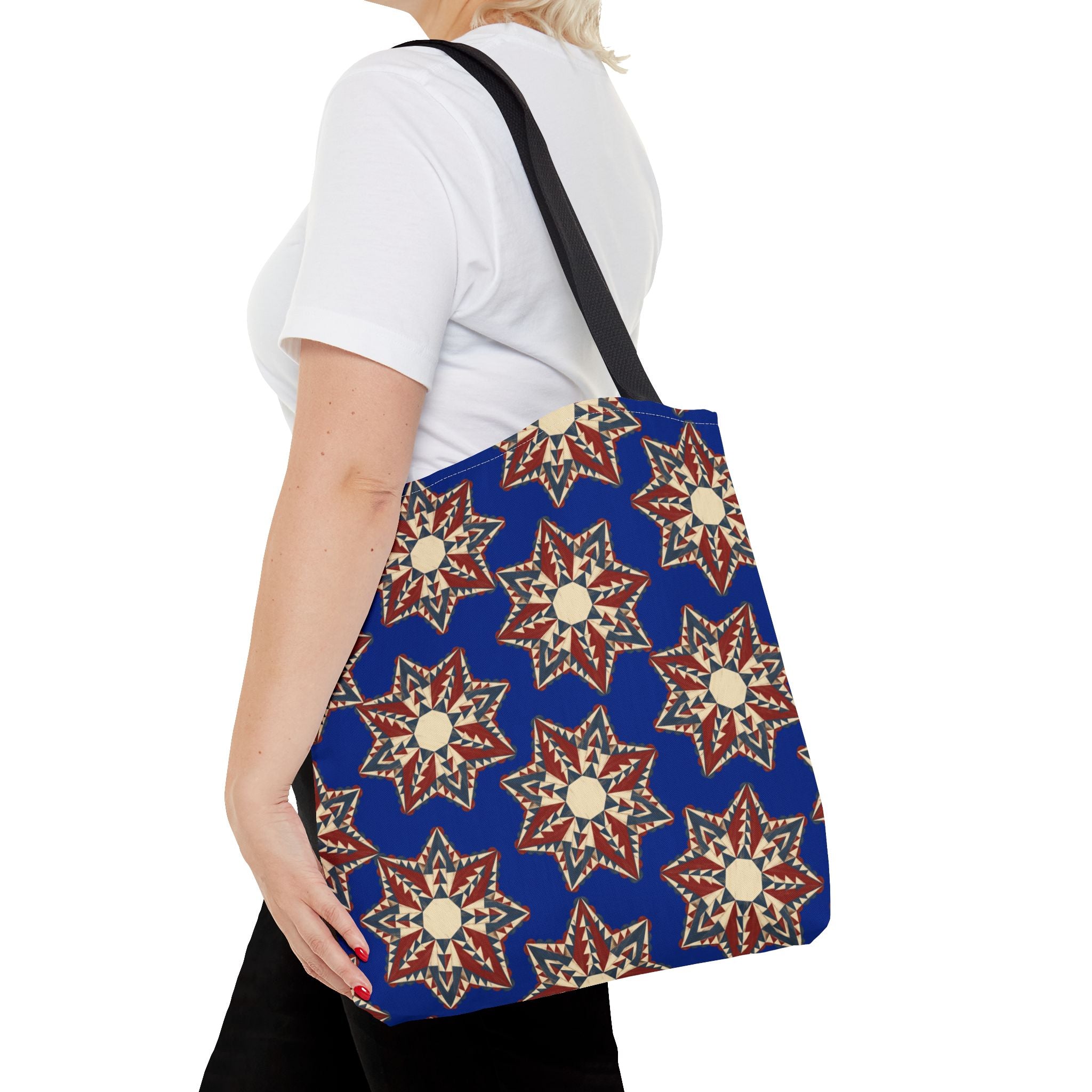 Blue tote bag with red and cream starburst floral pattern, black shoulder straps