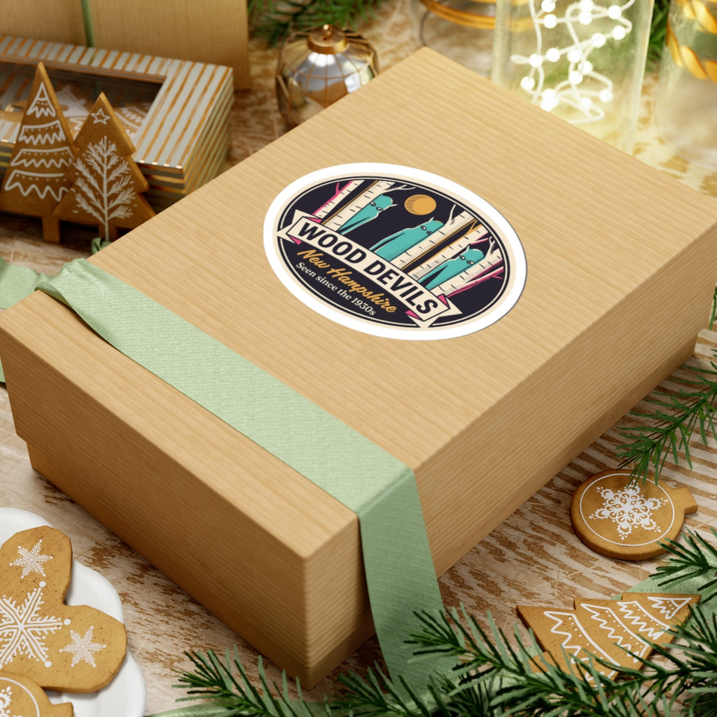 Wood Devils New Hampshire oval kiss-cut sticker on gift box, teal birch scene with gold moon