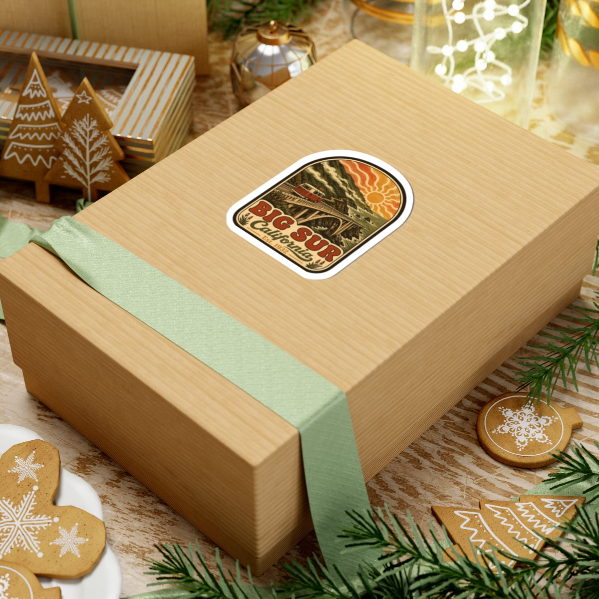 Kiss-cut Big Sur California sticker on wrapped gift box, vintage coastal bridge and camper van artwork.