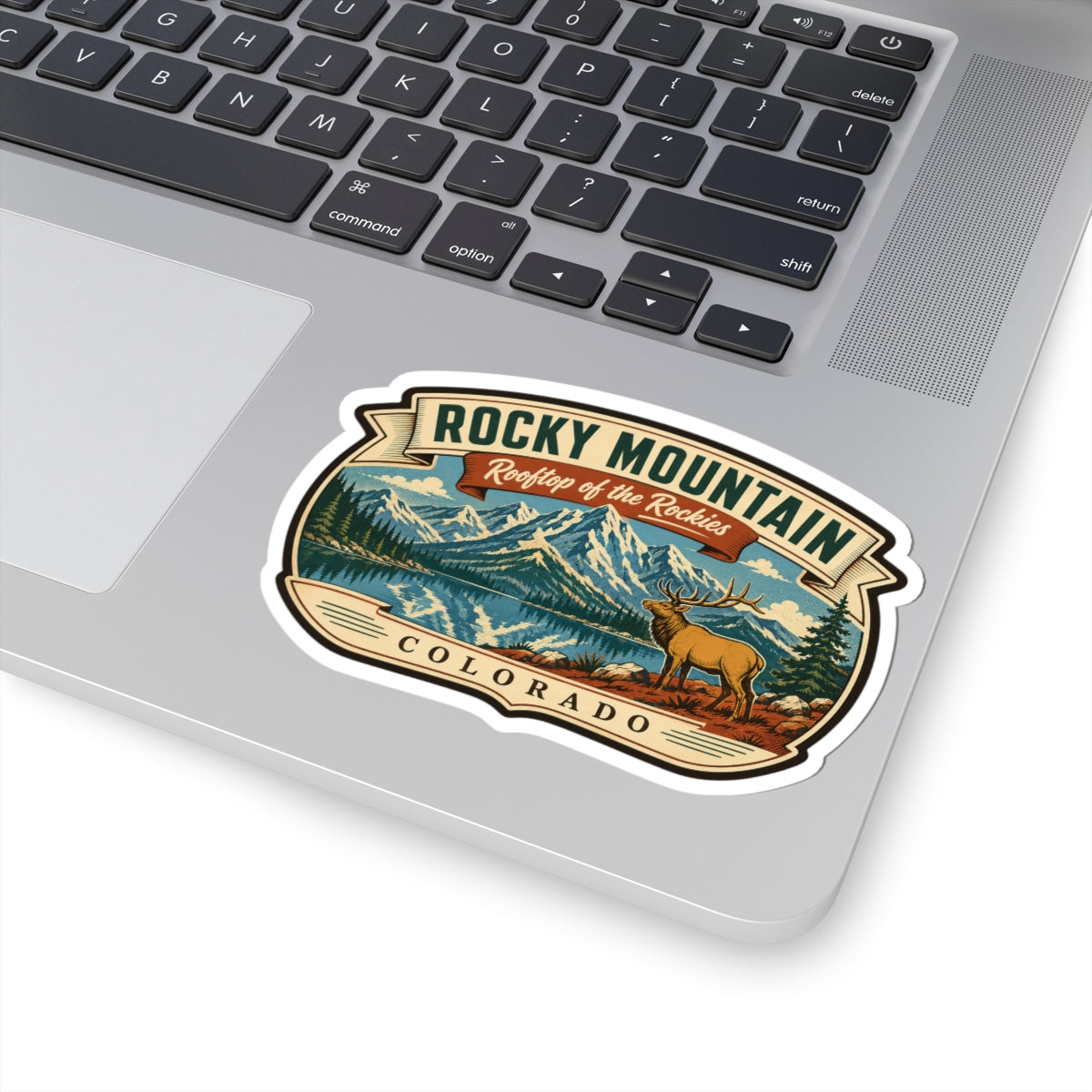 Travel sticker on a laptop lid, showing mountain lake landscape, elk, and Rocky Mountain Colorado