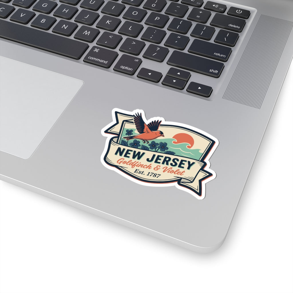 New Jersey bird-and-flower sticker on a laptop lid, vintage badge “Est. 1787”.