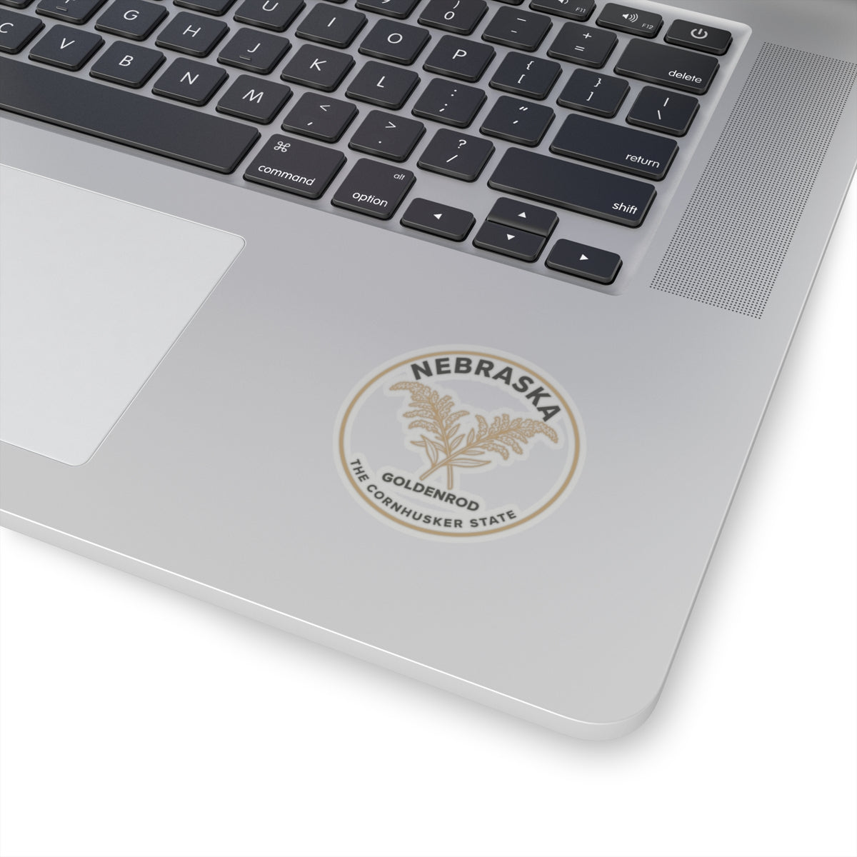 Transparent vinyl sticker placed on laptop lid with Nebraska goldenrod circular emblem