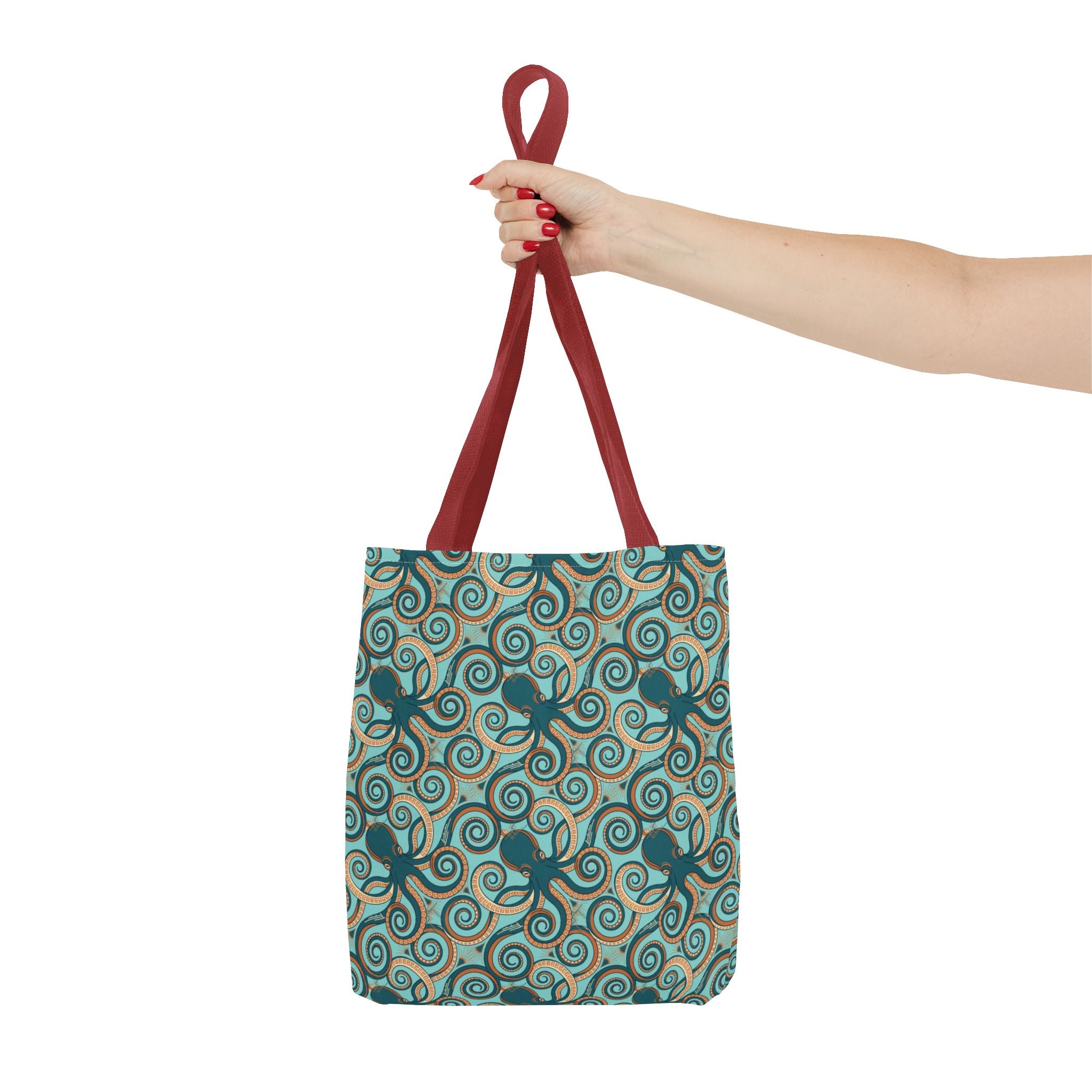 Teal octopus swirl tote bag with red handles, held overhead