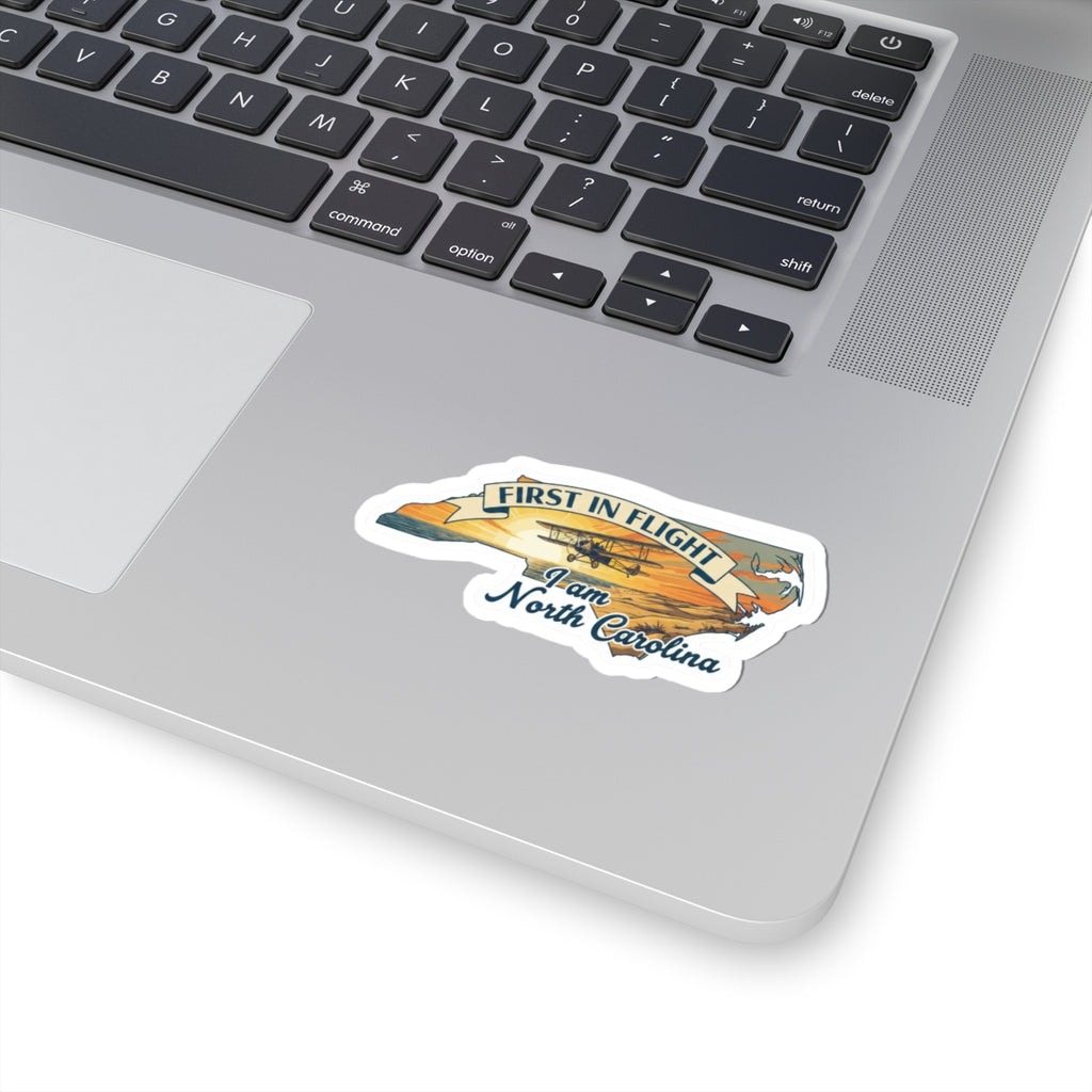 First in Flight North Carolina sticker on laptop, airplane graphic and “9 am North Carolina”.