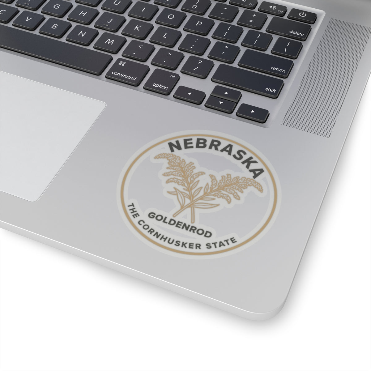 Transparent vinyl sticker on laptop lid showing Nebraska goldenrod state text