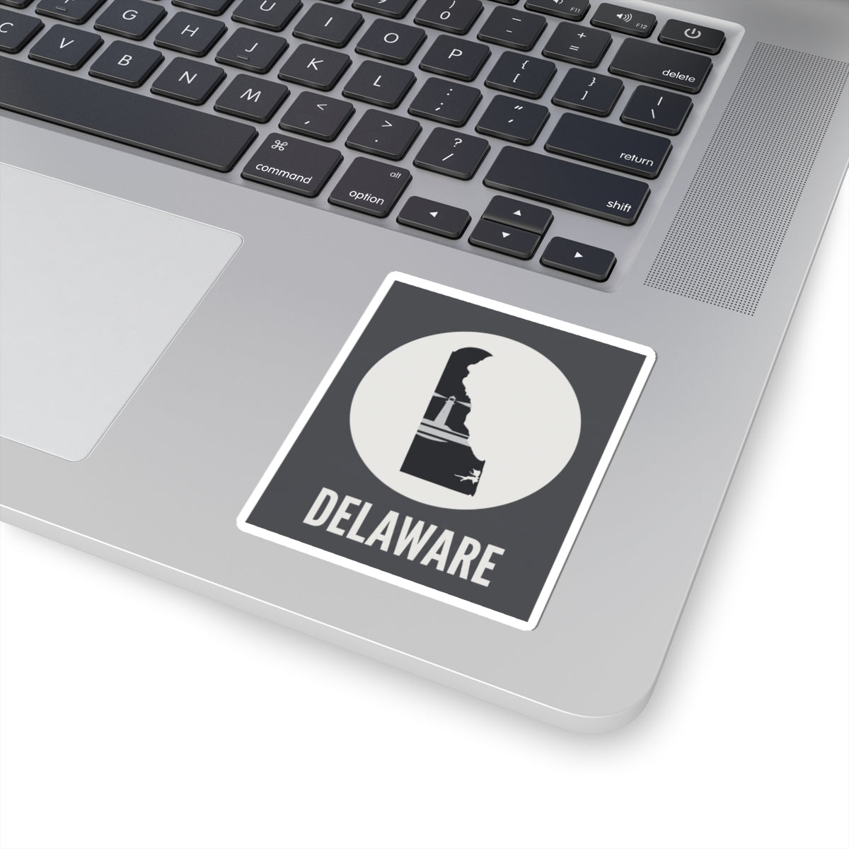 Delaware state silhouette sticker on laptop lid, white circle badge and DELAWARE text