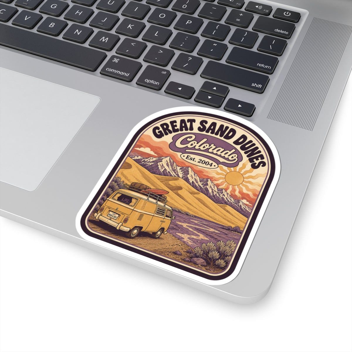 Rounded Great Sand Dunes Colorado sticker on laptop; desert dunes with vintage camper and sun