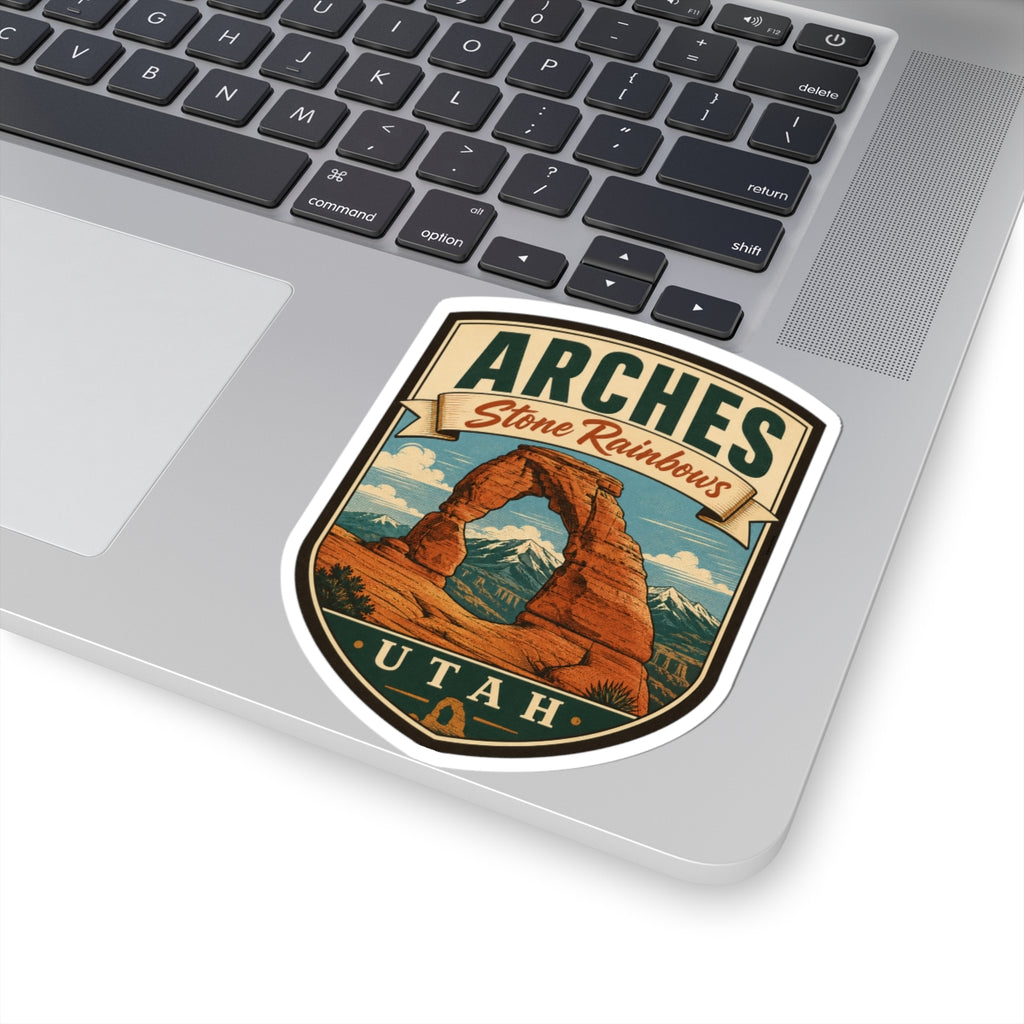 Shield-shaped Arches Utah kiss-cut sticker featuring Delicate Arch under Stone Rainbows lettering, angled