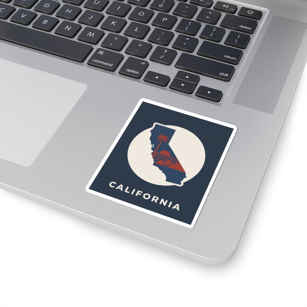 California silhouette sticker on laptop keyboard: navy square, white circle, red sunset, "CALIFORNIA"