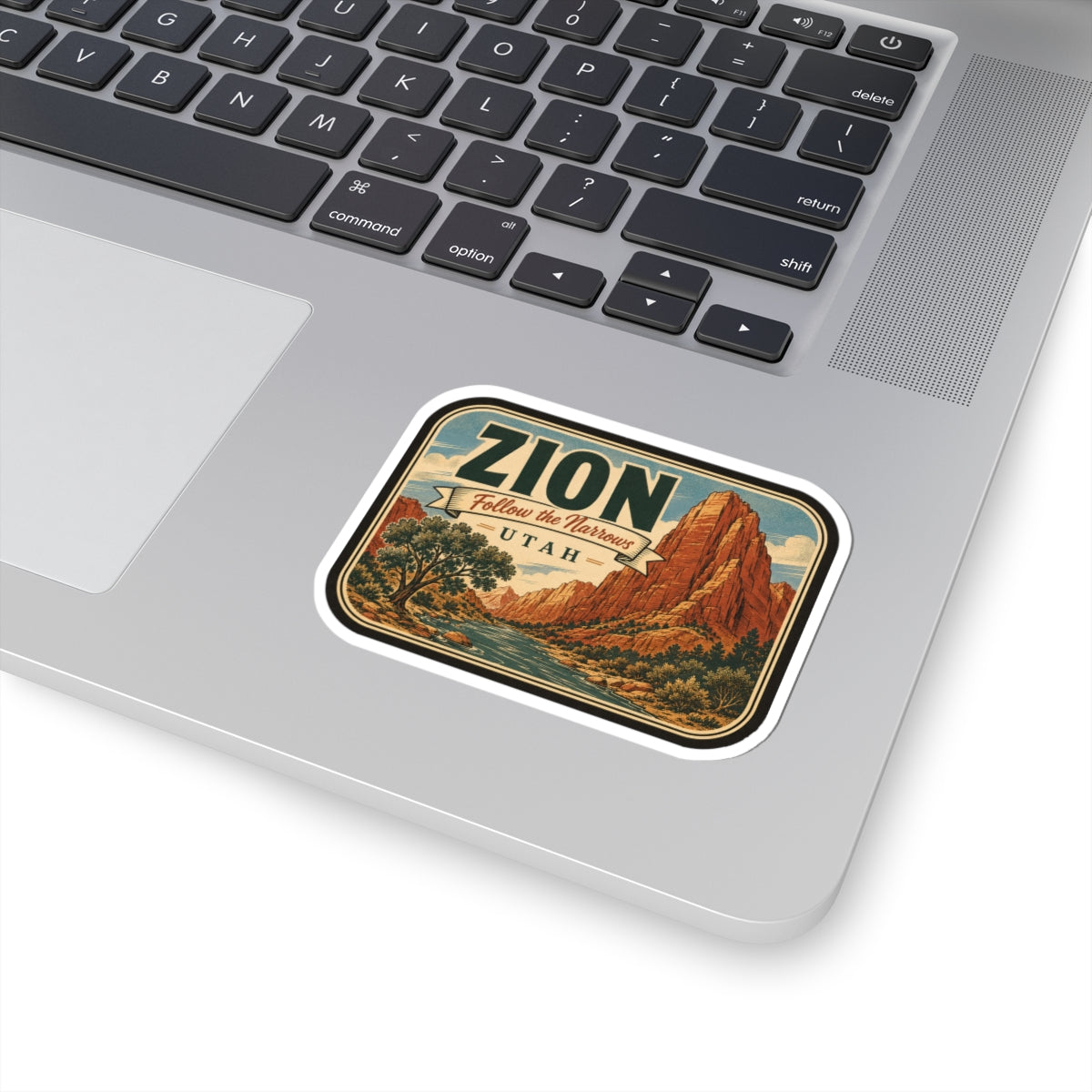 Zion sticker on laptop keyboard, rounded border with canyon art, “UTAH,” and “ZION”