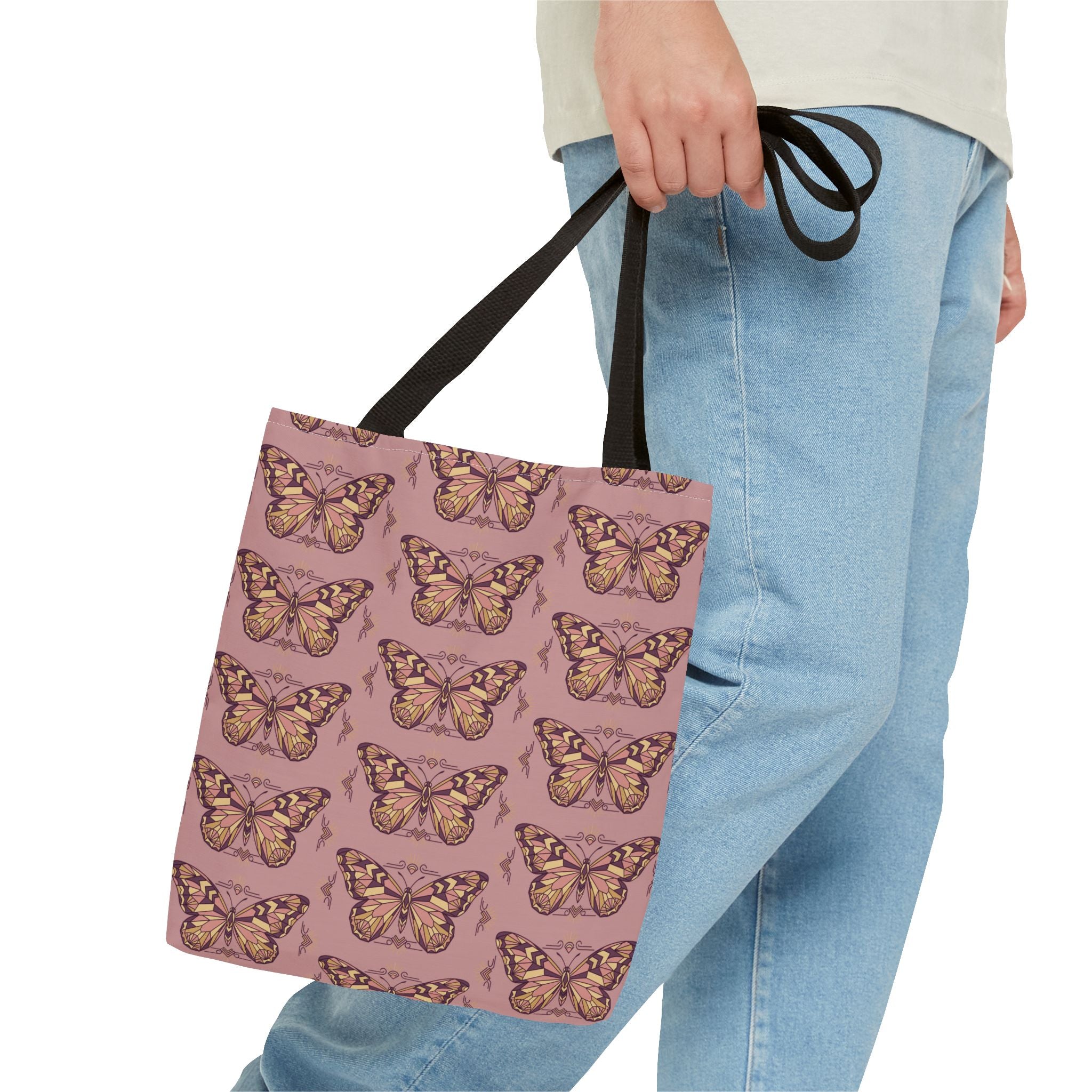 Pink butterfly print tote bag with black straps, carried by hand