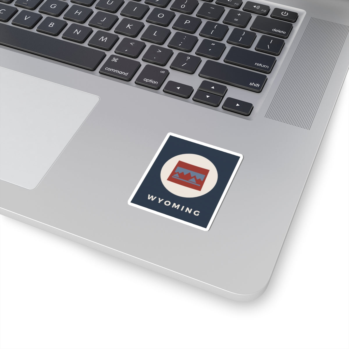 Square Wyoming map badge kiss-cut sticker with WYOMING text and mountain flag colors.