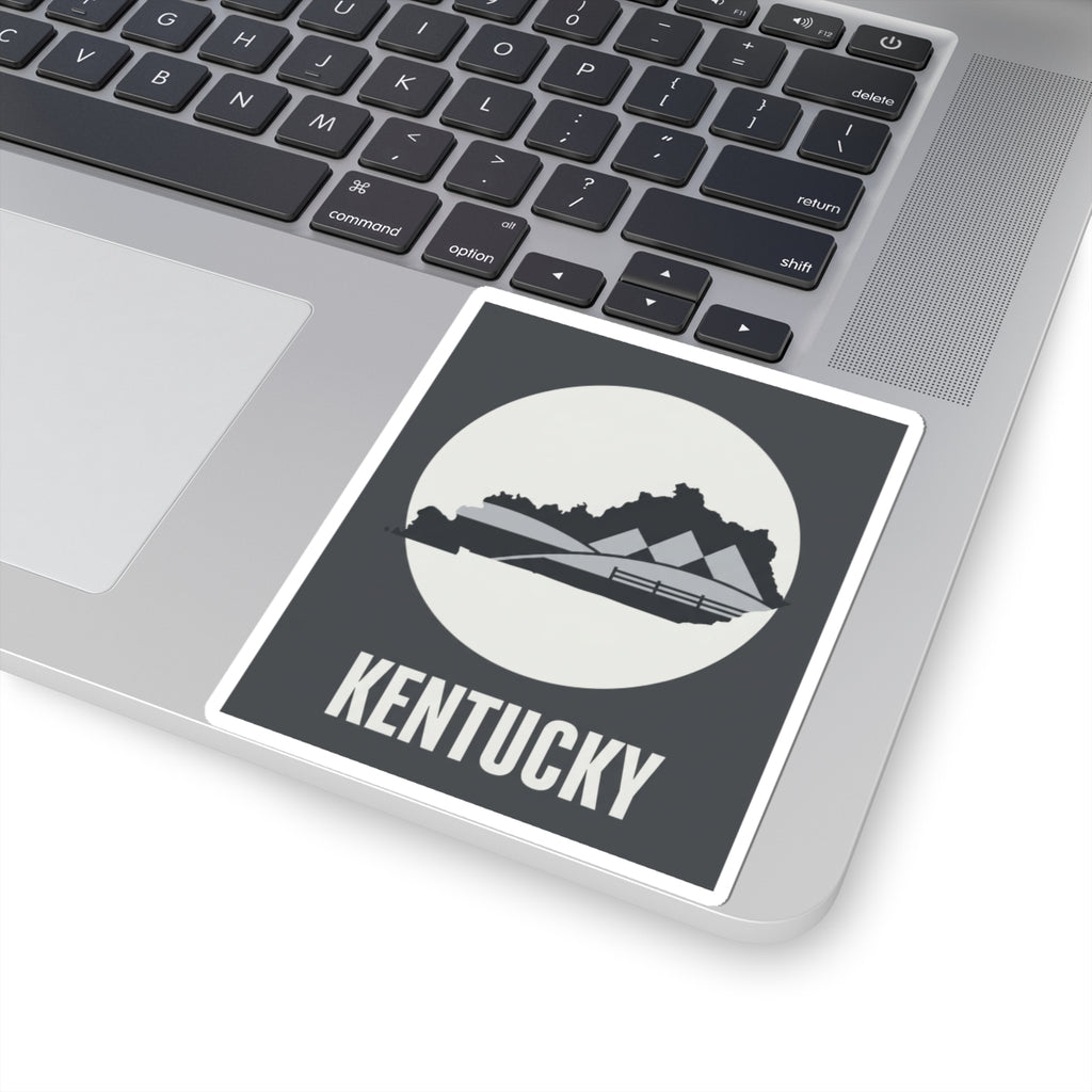 Kentucky vinyl sticker on laptop keyboard, dark gray square with white border and KENTUCKY