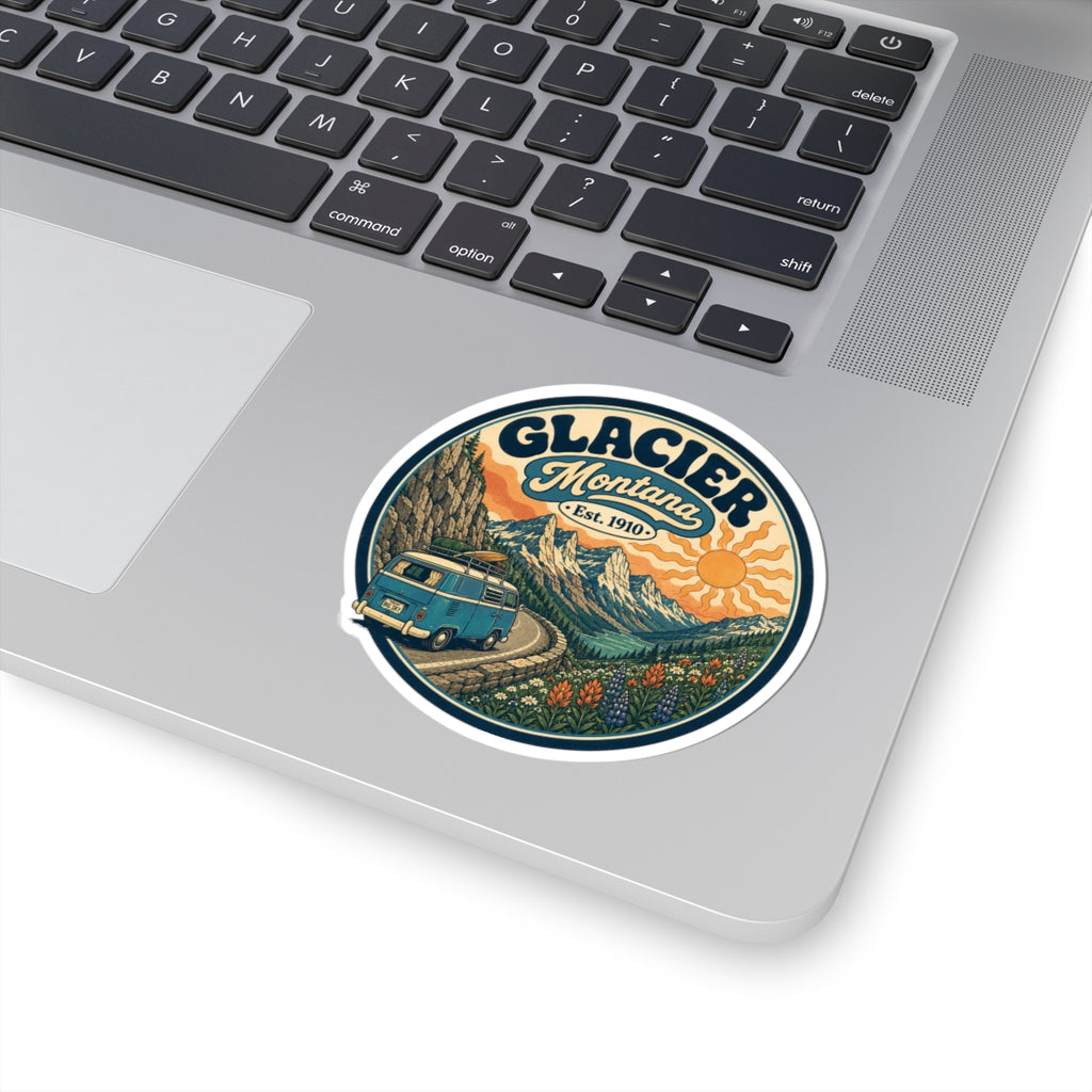 Round kiss-cut sticker with Glacier Montana typography, teal camper van, mountains, and orange sun