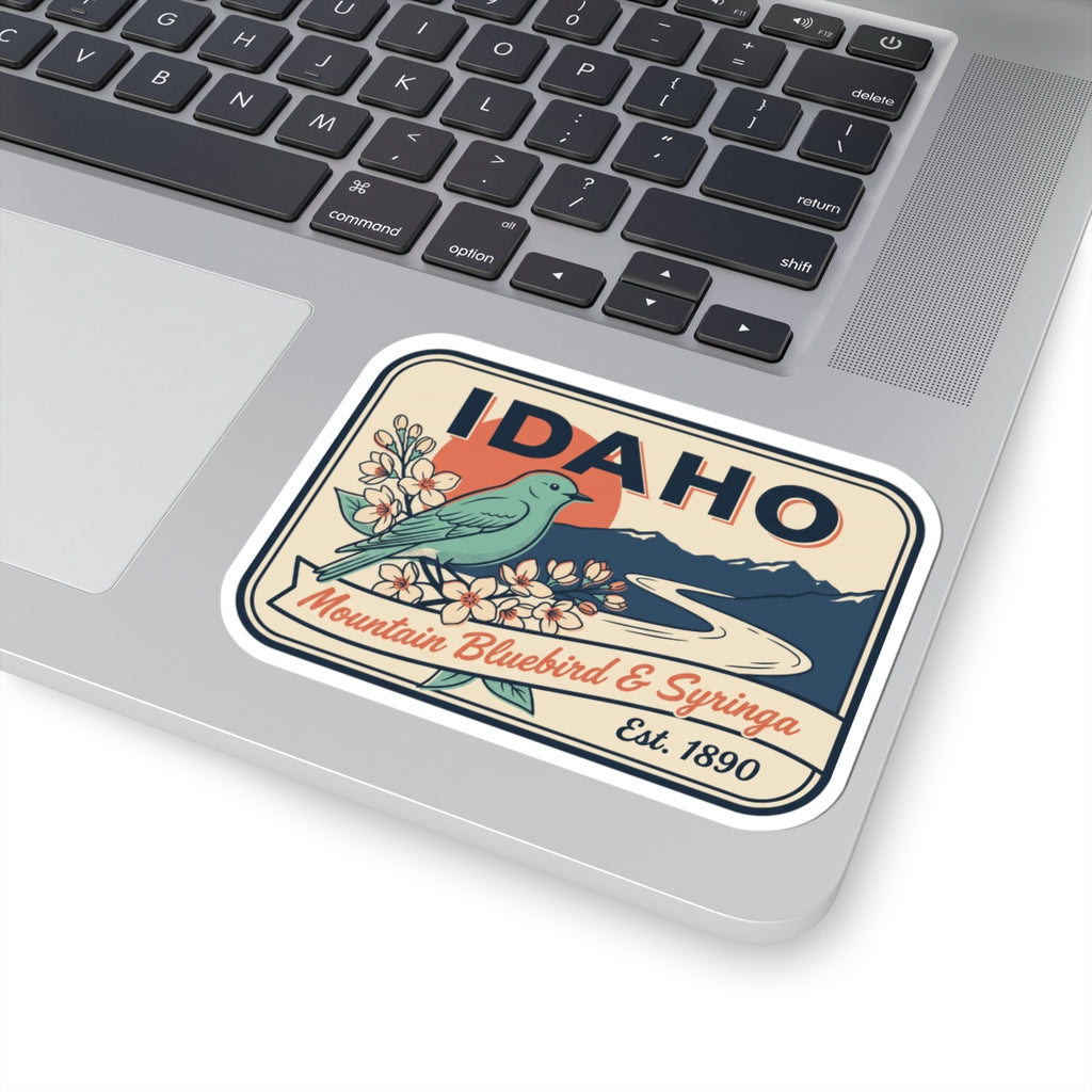 Rounded sticker placed on laptop trackpad, IDAHO with bluebird and mountains
