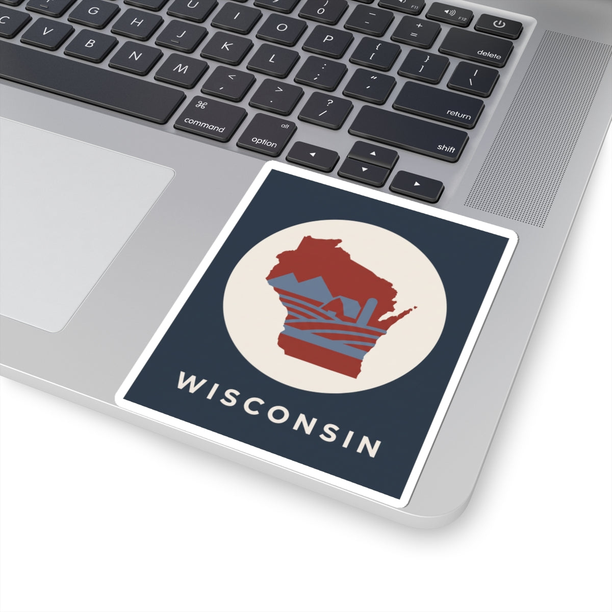 Wisconsin badge sticker on laptop: red map in cream circle with WISCONSIN lettering