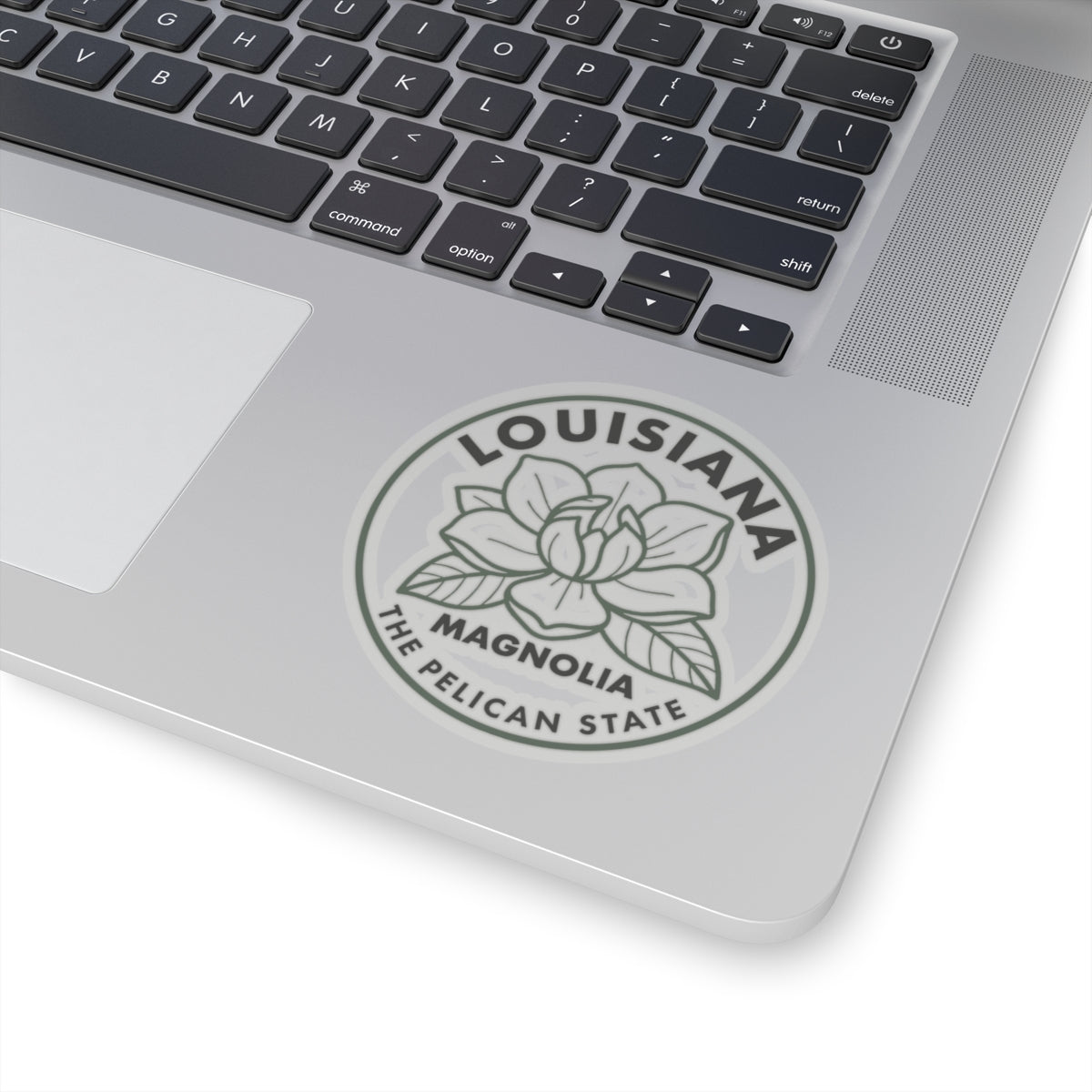 Transparent vinyl round Louisiana magnolia sticker on laptop lid, centered gray flower emblem