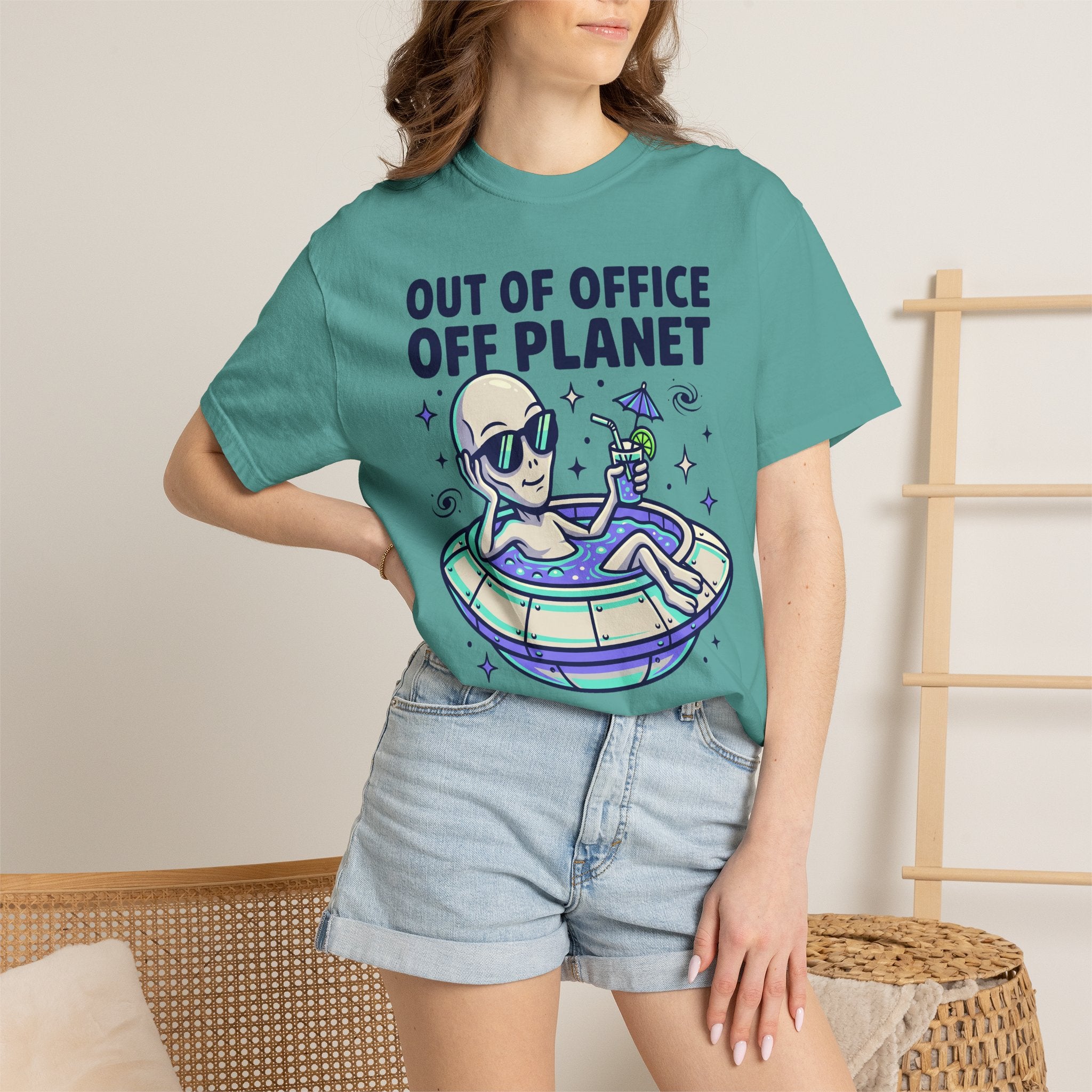 Teal T-shirt worn by model with alien astronaut floatie graphic and blue text