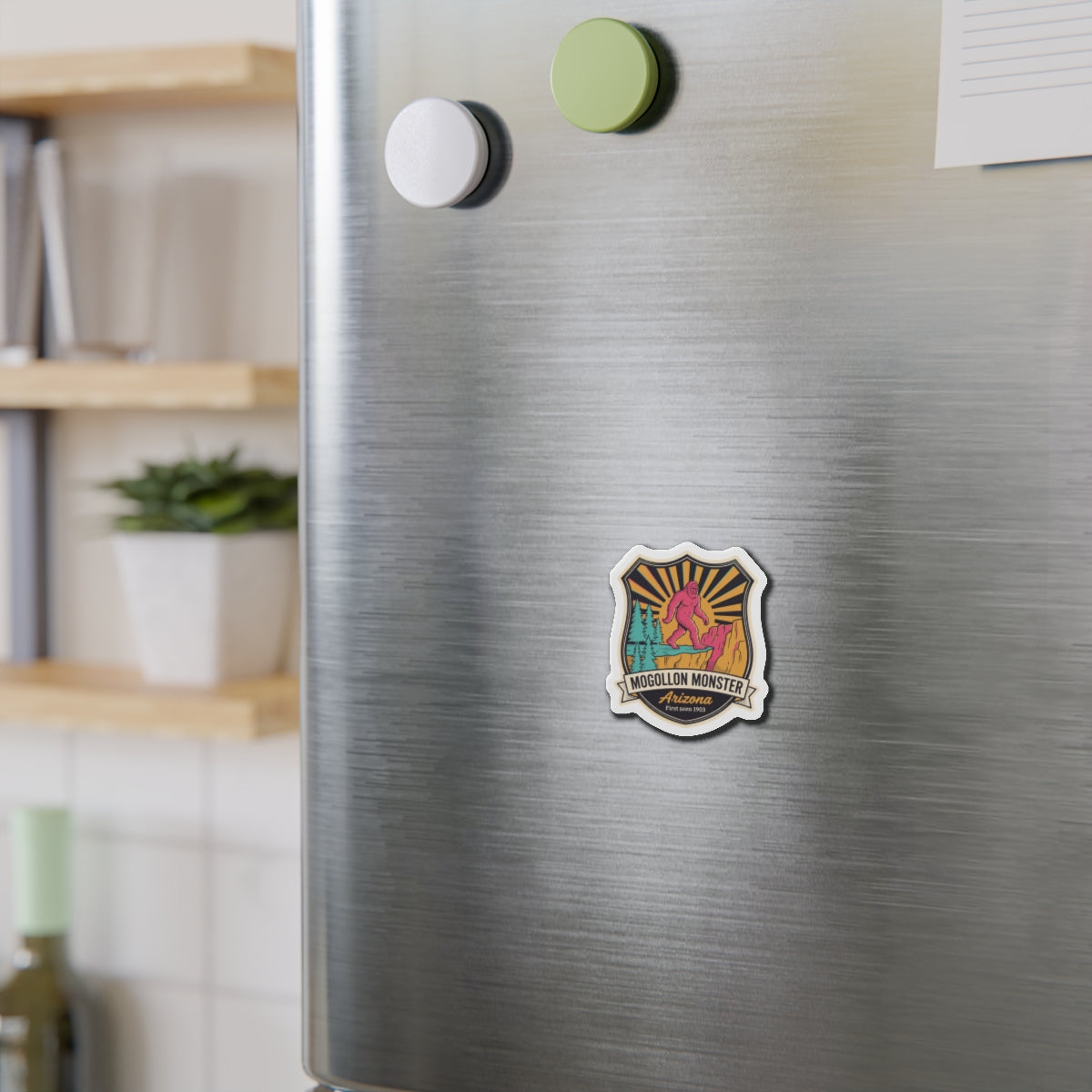 Die-cut Mogollon Monster Arizona magnet badge on brushed stainless fridge, centered