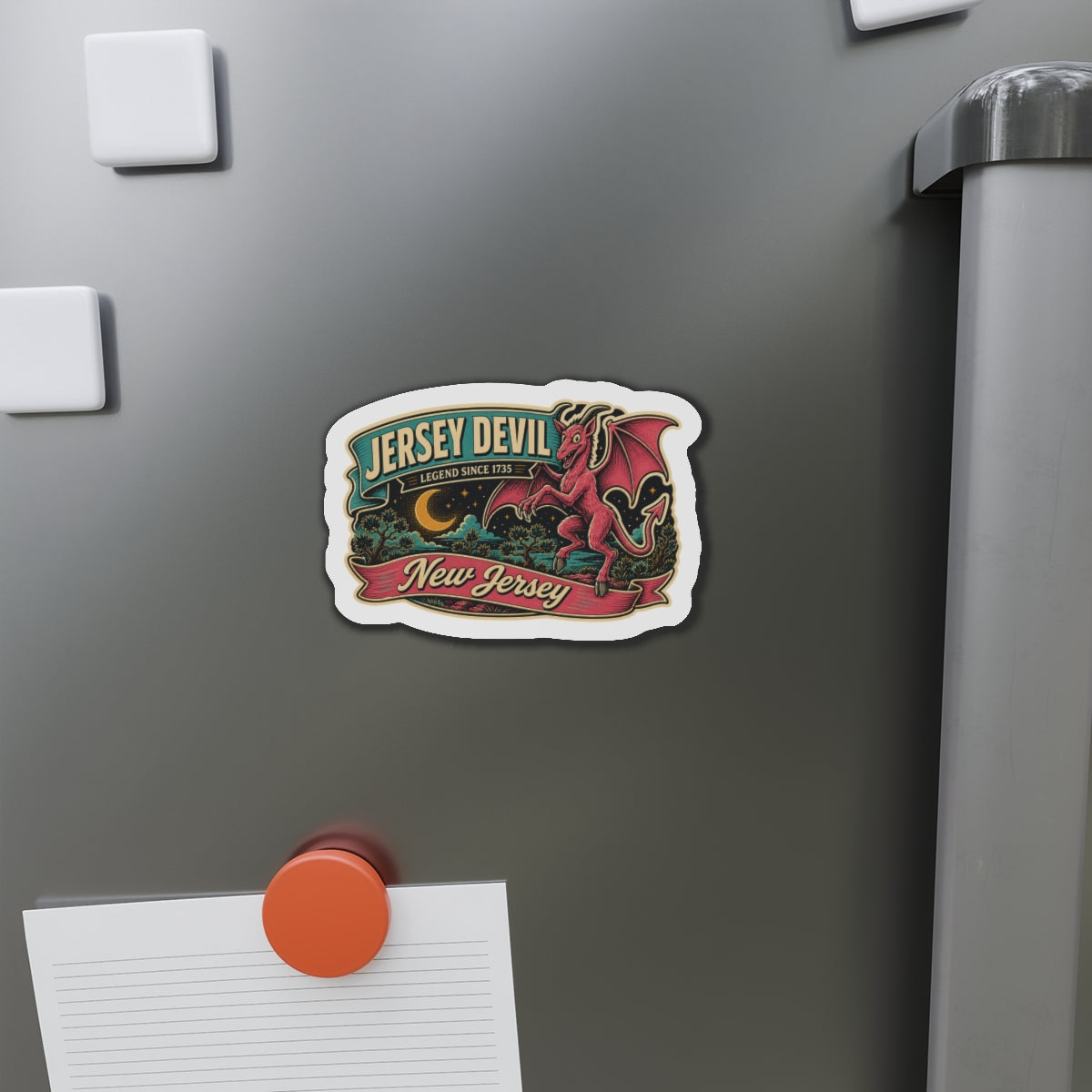 Die-cut Jersey Devil magnet on refrigerator door near sticky notes, small bordered emblem.