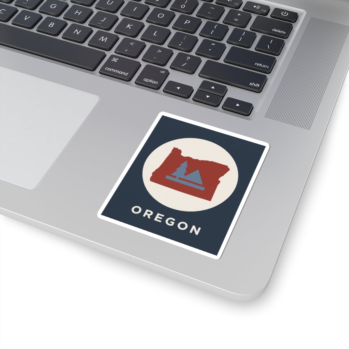 Square dark-blue sticker showing Oregon map with pine and mountain illustration; reads OREGON.