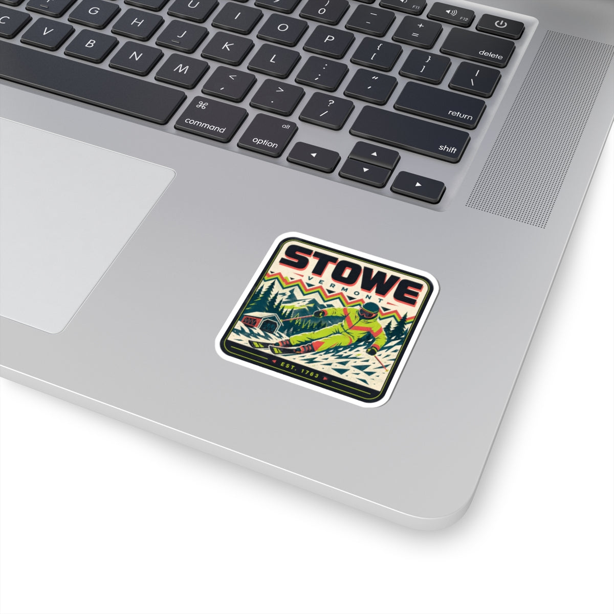 White kiss-cut vinyl travel sticker with Stowe skier graphic on laptop