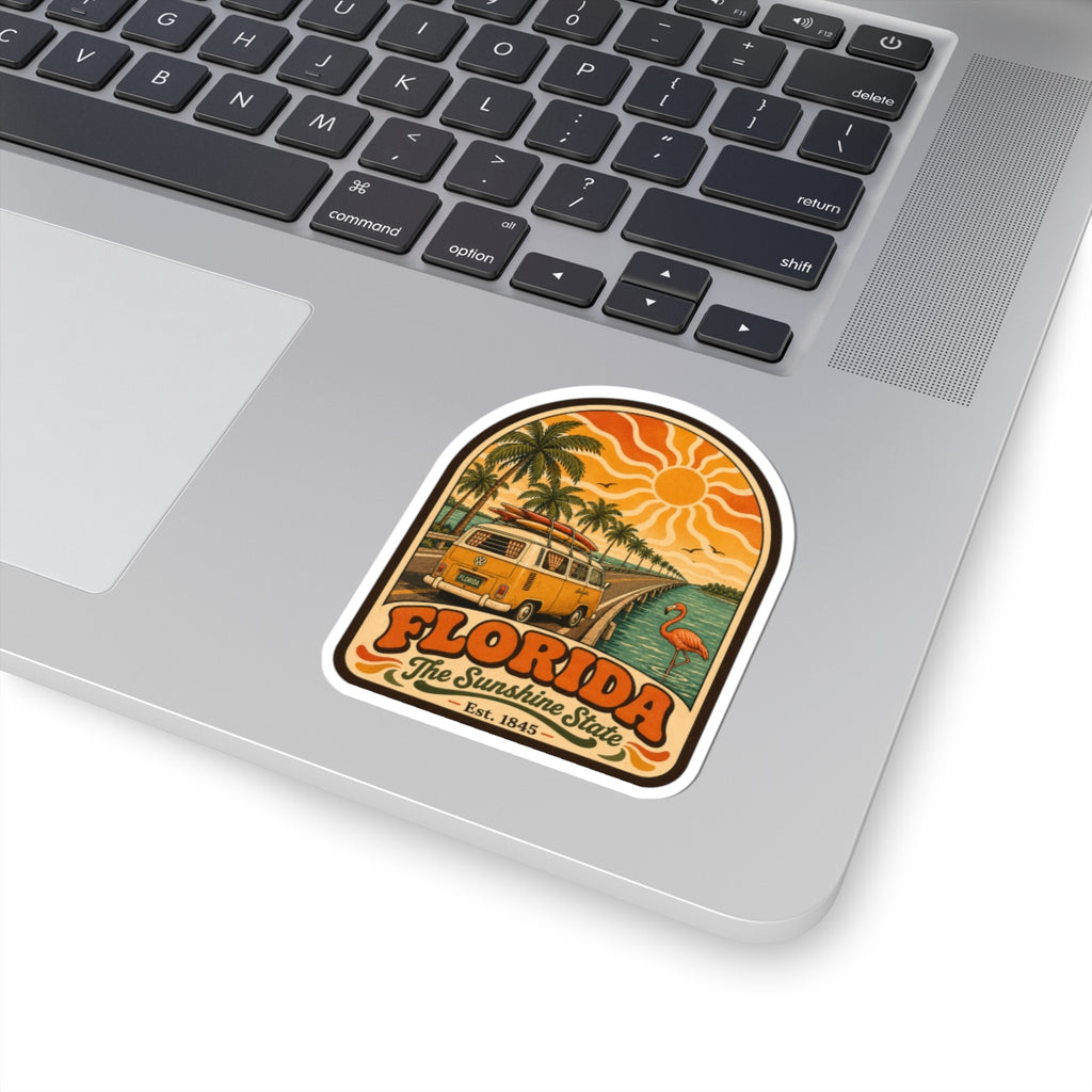 Florida surf bus decal on laptop keyboard, featuring palm trees, sun rays, and flamingo