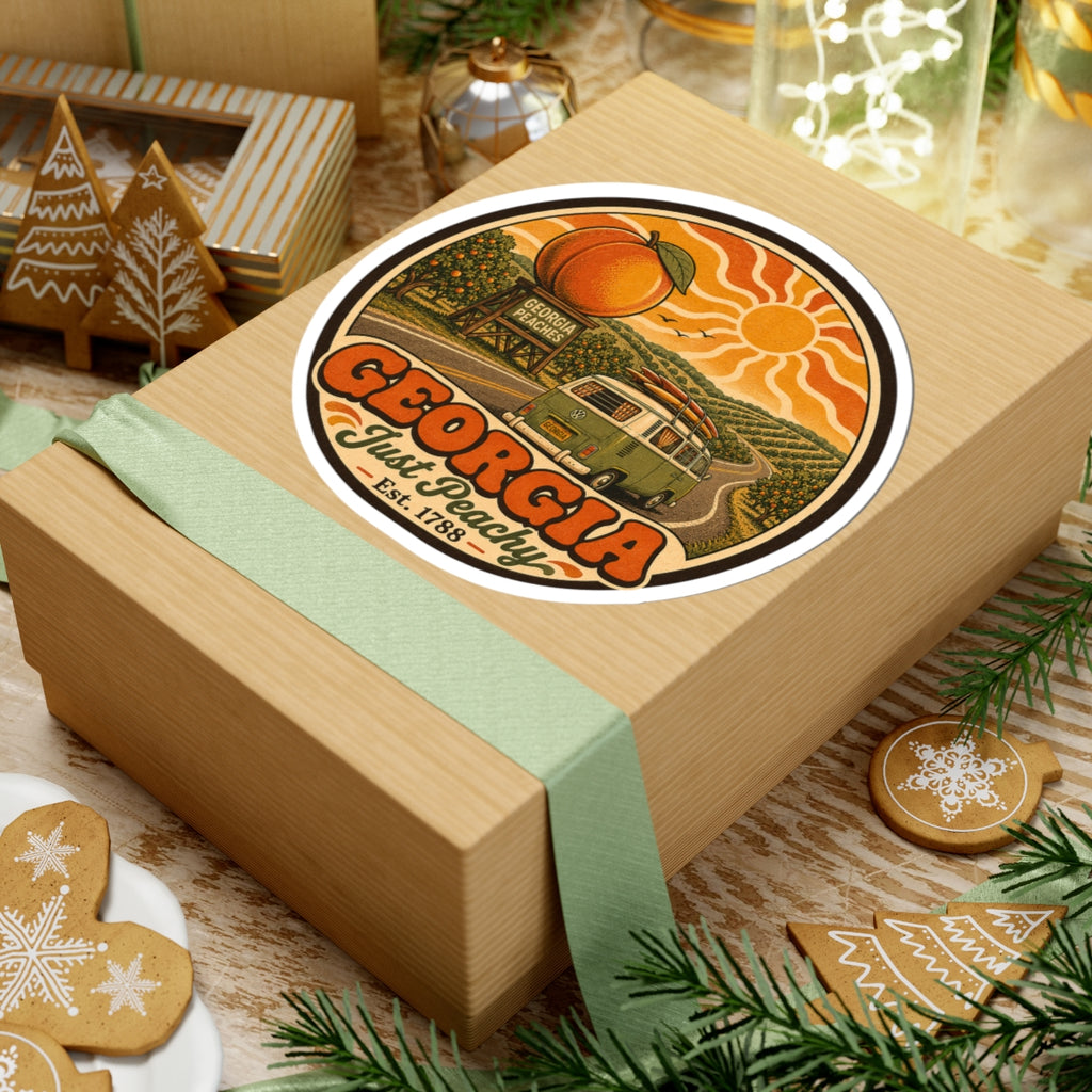 Round vinyl sticker on tan gift box lid, showing Georgia Just Peachy orange peaches and green van