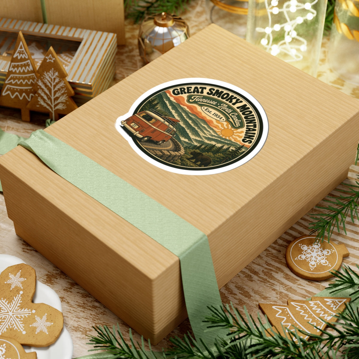Round sticker on a wrapped present: vintage camper van above layered pine mountain hills