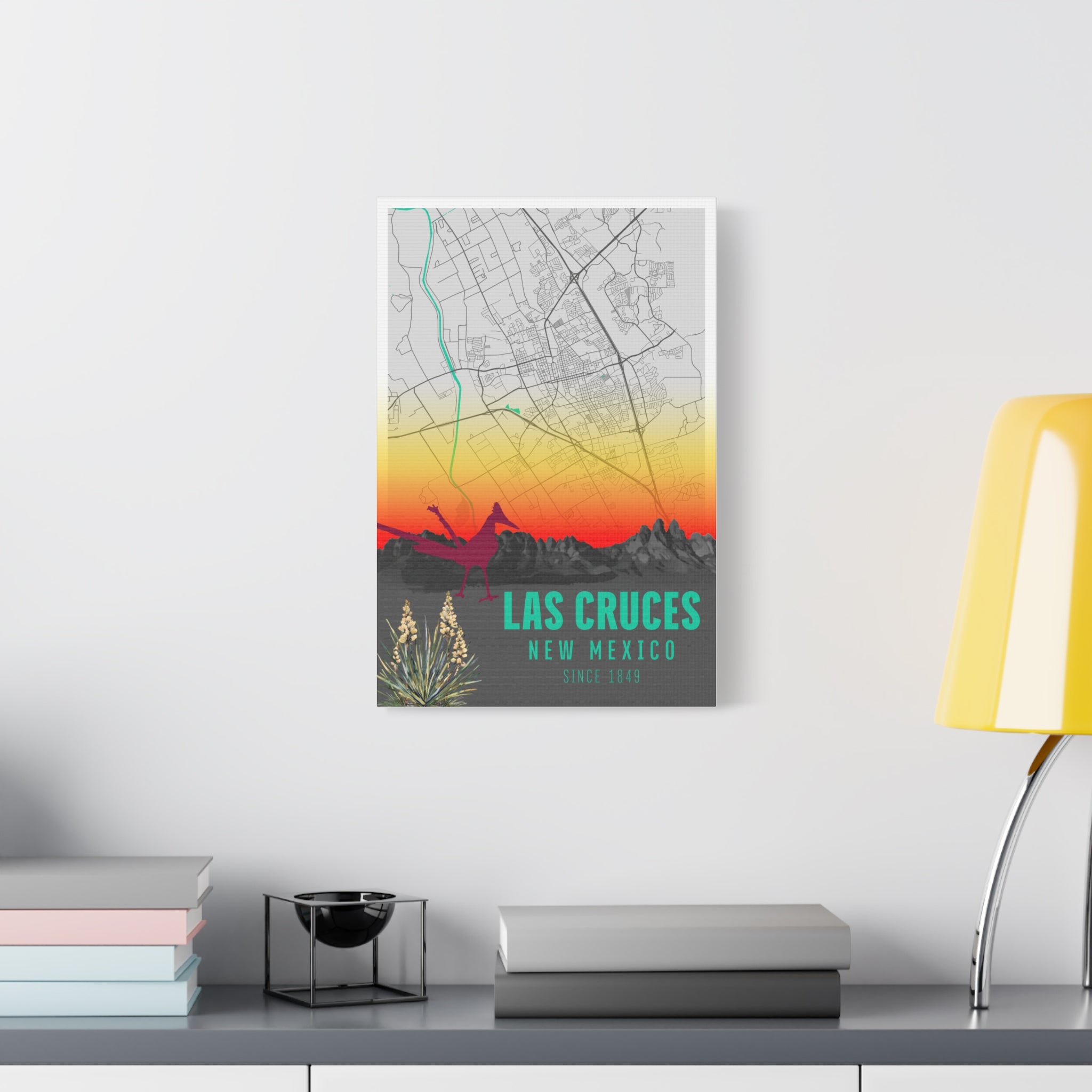 Las Cruces New Mexico map canvas on wall above shelves, 'Las Cruces' teal text visible