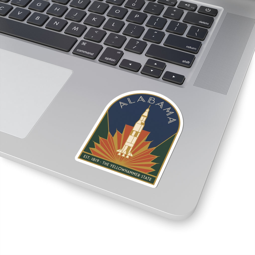 Small Alabama rocket vinyl sticker on laptop lid, arched tower and sunburst design