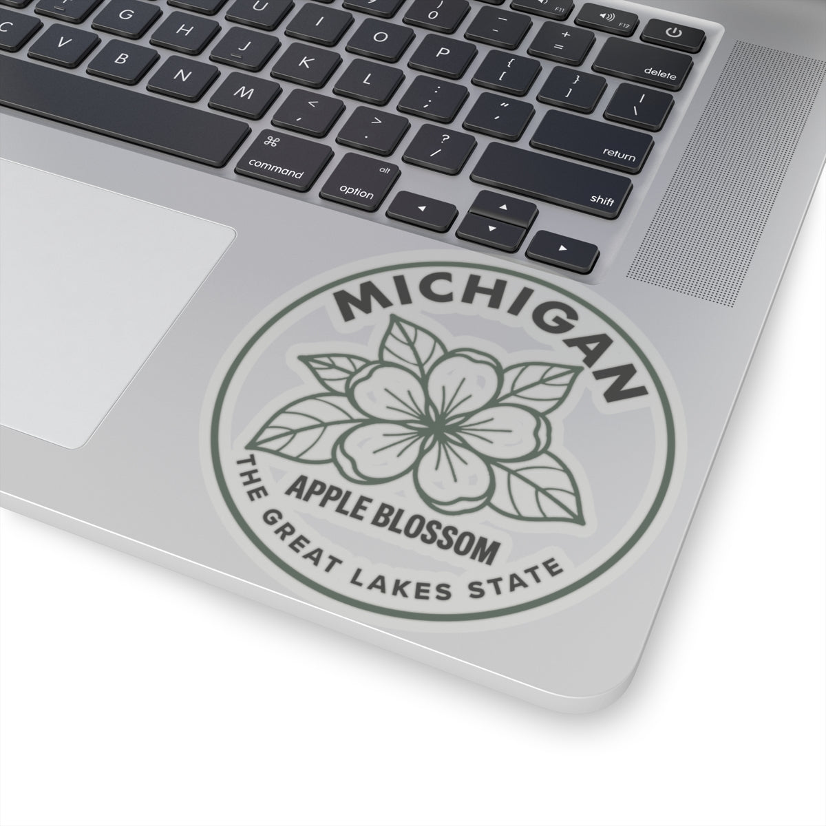 Circular Michigan apple blossom transparent vinyl sticker on laptop, gray floral logo seal