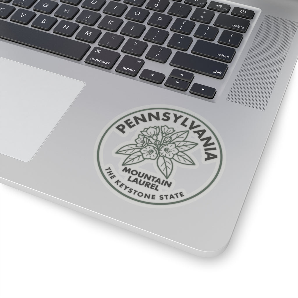 Transparent vinyl sticker on laptop trackpad, circular Pennsylvania Mountain Laurel seal