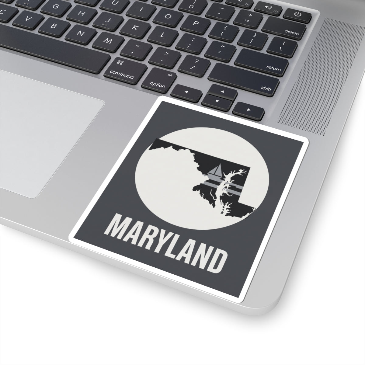 Maryland kiss-cut sticker on laptop lid, featuring circle state silhouette and “MARYLAND”
