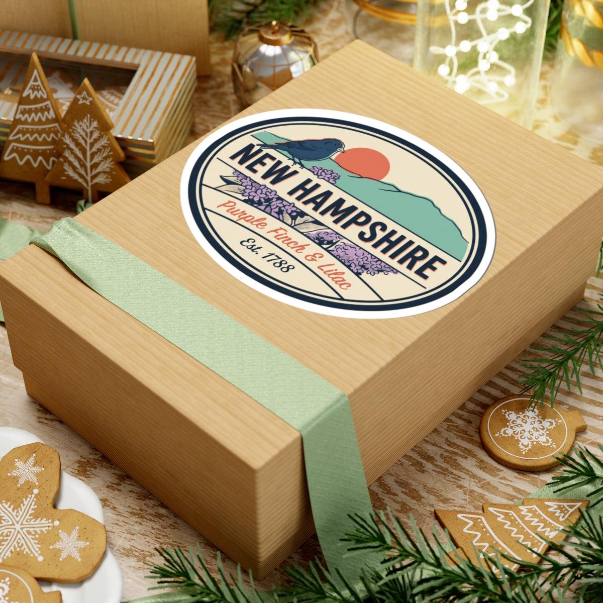 Round New Hampshire sticker centered on a gift box showing purple finch and lilac, Est. 1788