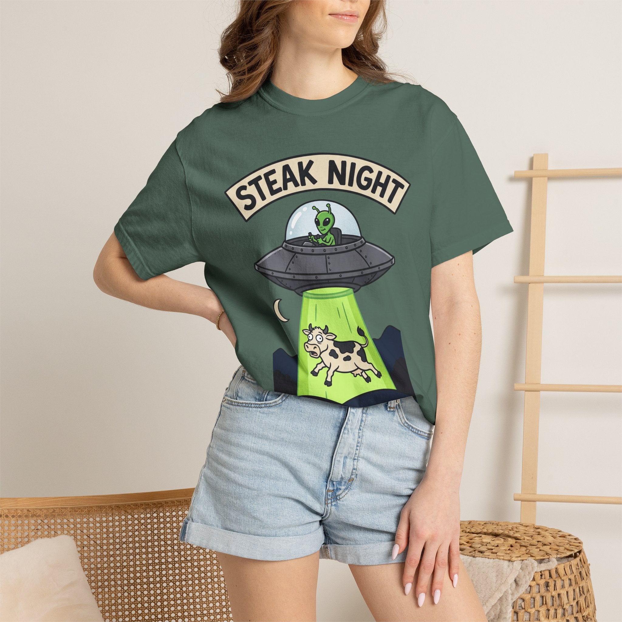 Forest green graphic T-shirt on model, 'STEAK NIGHT' UFO and alien cow print.