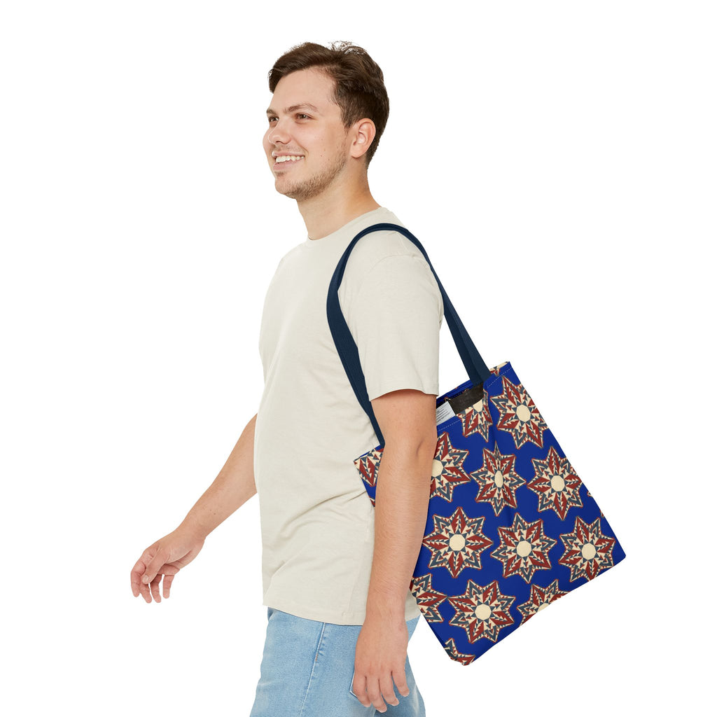 Starburst floral tote bag in blue with red and cream star motifs, worn over shoulder.