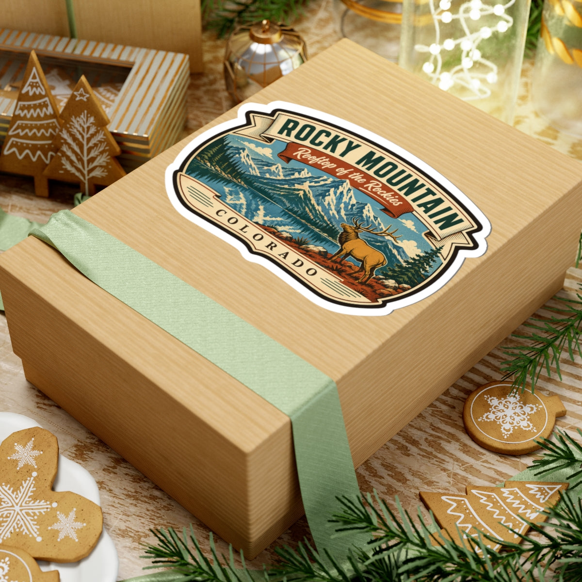 Travel sticker on a wrapped gift box, showing Rocky Mountain lettering, elk, and Colorado
