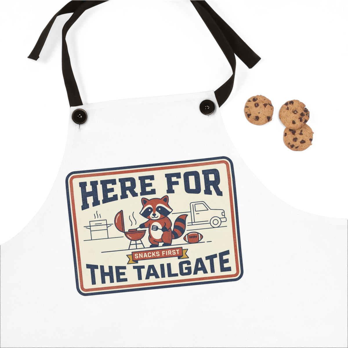 White apron with black straps and 'Here for the Tailgate' raccoon logo patch