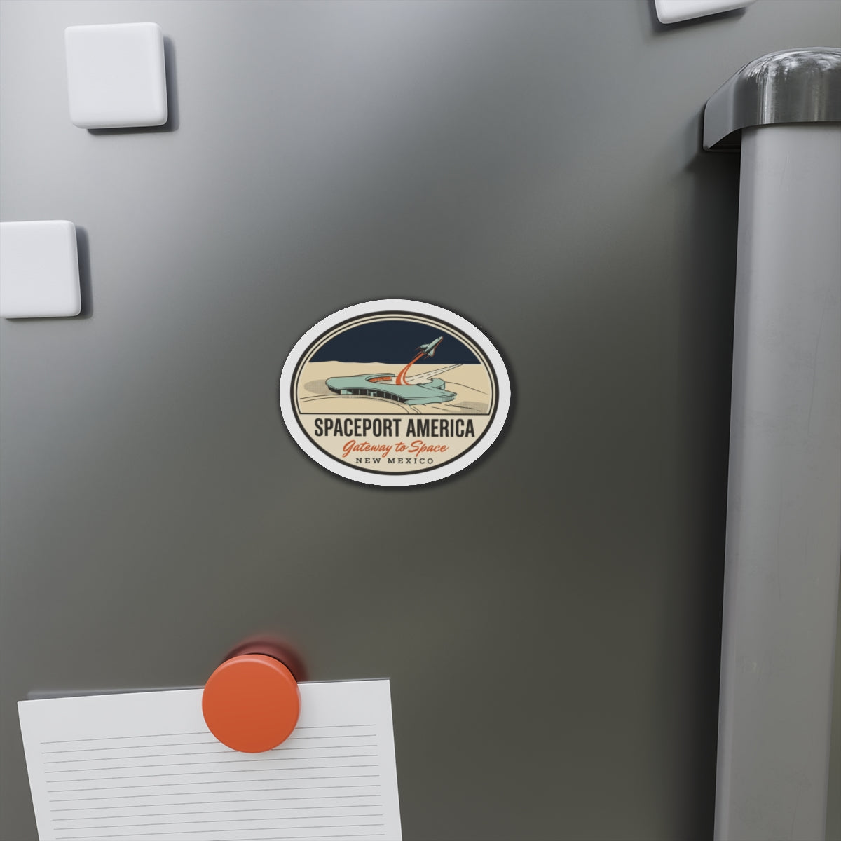Spaceport America rocket emblem magnet on a refrigerator door near paper notes