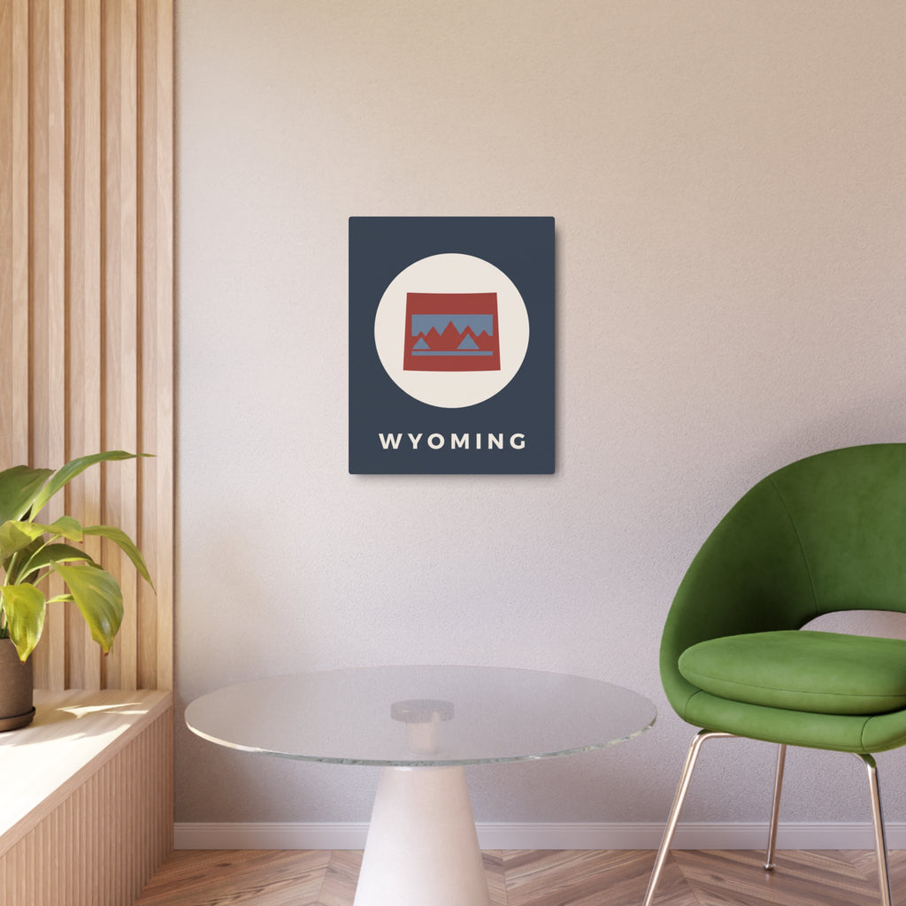 Wyoming state metal art sign on wall, dark blue square with oval mountains badge and “WYOMING”.