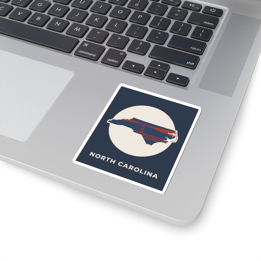 North Carolina state kiss-cut sticker on a laptop keyboard, navy square with map graphic