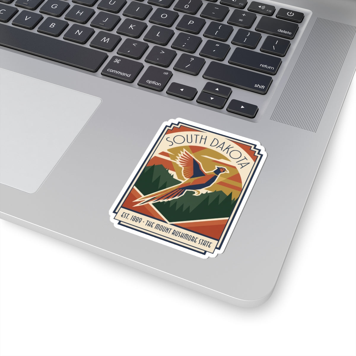Die-cut vinyl sticker placed on a laptop keyboard featuring SOUTH DAKOTA pheasant art
