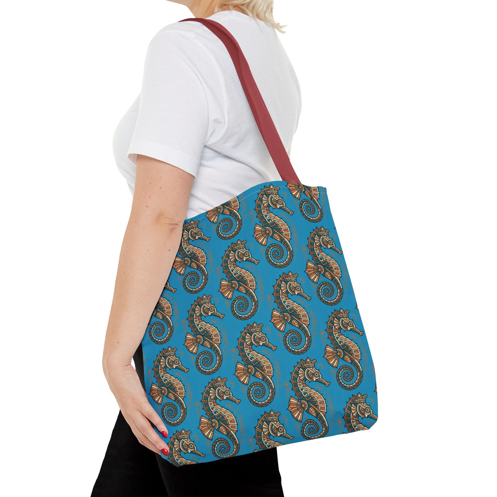 Tote bag side view in blue with all-over seahorse pattern and red straps