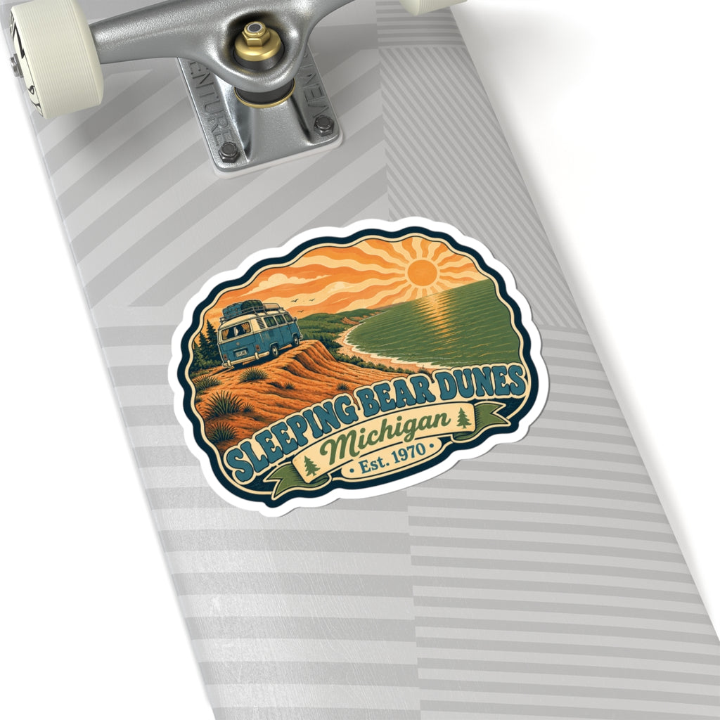 Die-cut sticker showing camper van on dunes overlooking a green lake with sunrise and Est. 1970
