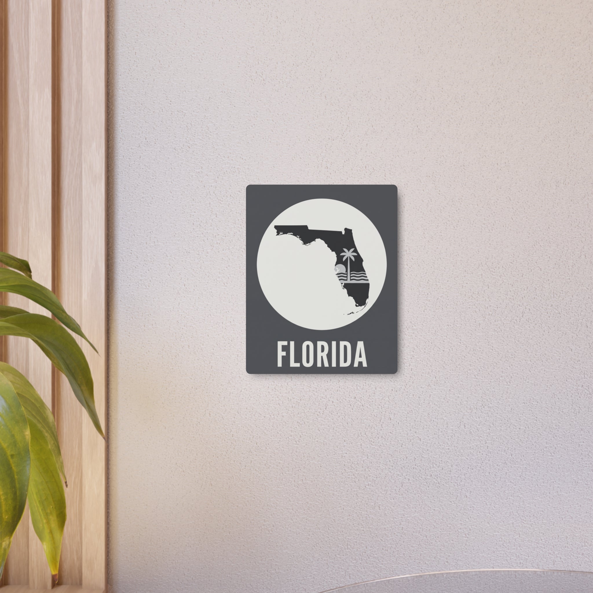 Small square Florida state silhouette metal wall art on wall with “FLORIDA” text