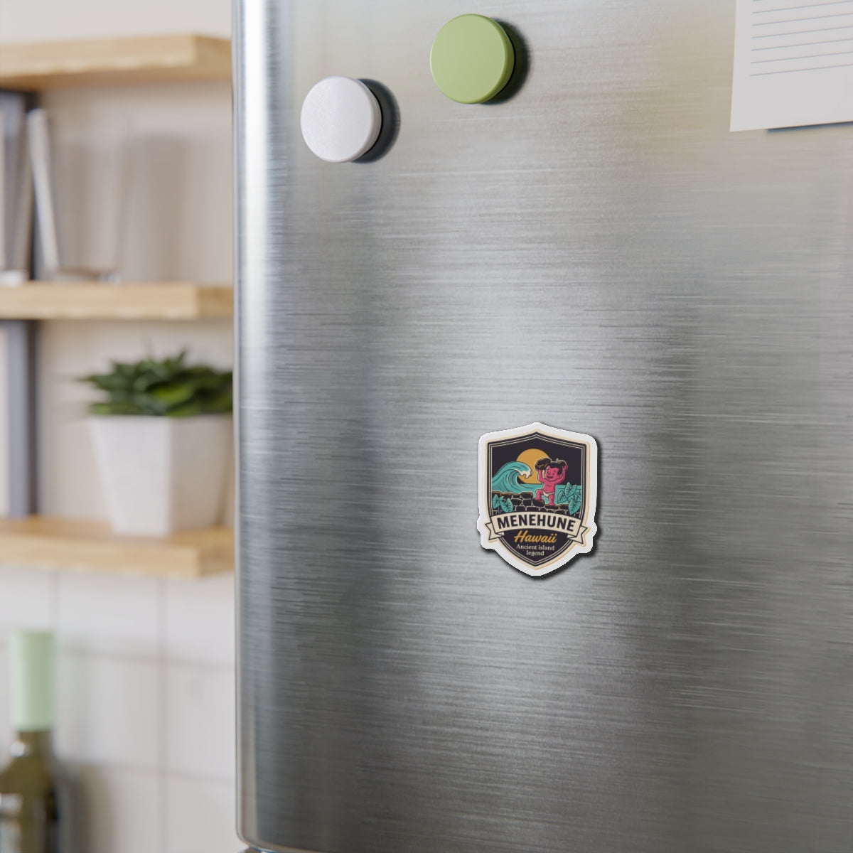 Shield-shaped die-cut magnet detail with wave and pink character, “Menehune Hawaii” text