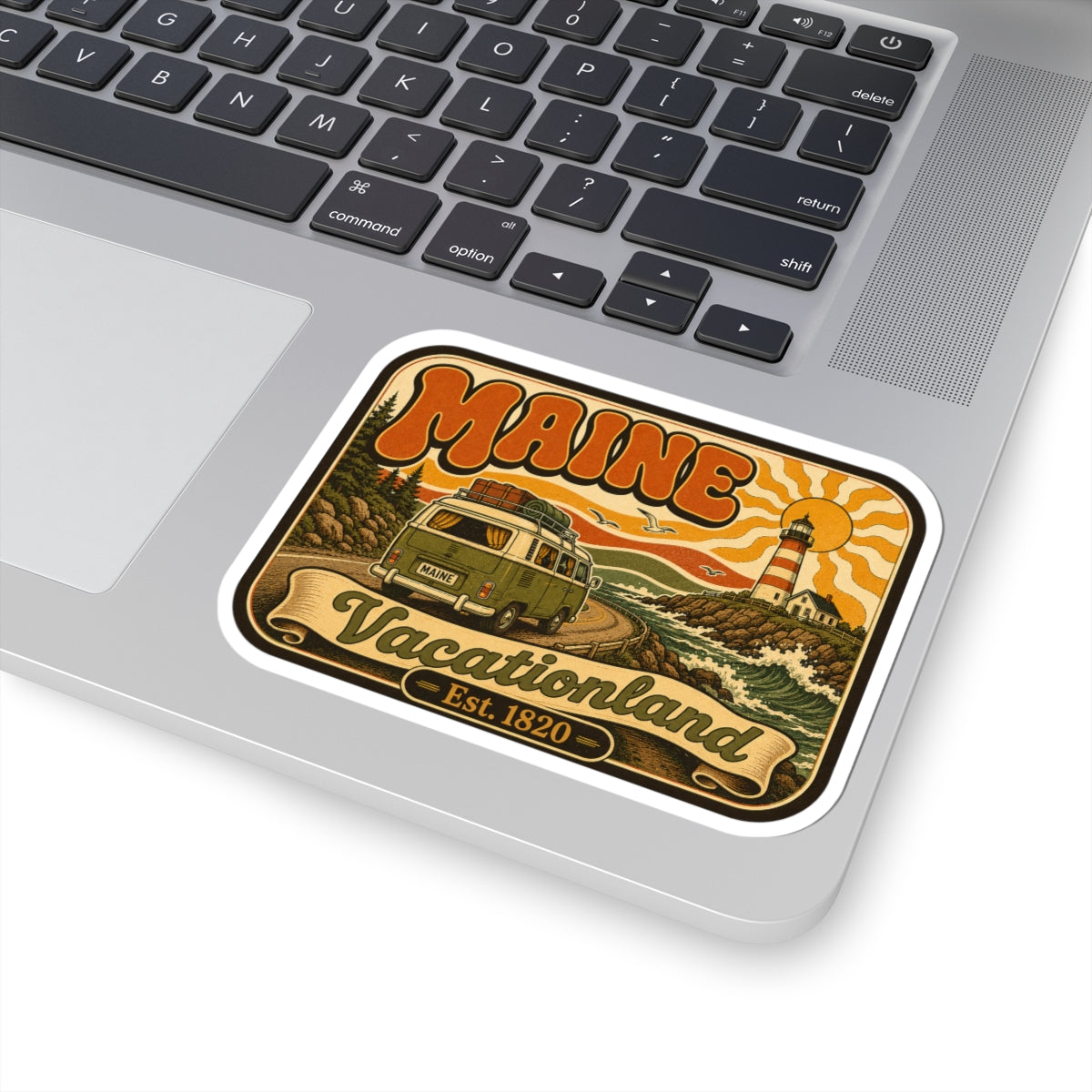 Retro roadtrip kiss-cut sticker on laptop trackpad, lighthouse and camper van artwork